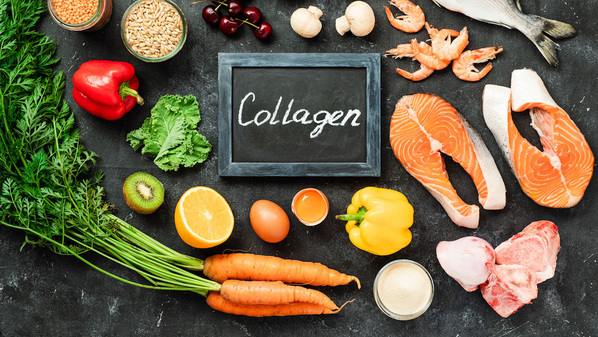 Assortment of foods that support collagen production including chicken, fish, carrots, kiwi, bell pepper, and collagen powder.