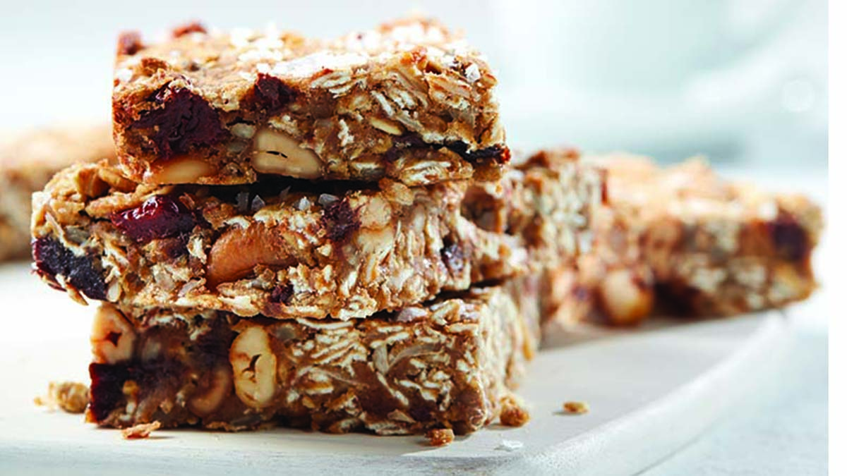 A plate of a stack of three cannellini cashew breakfast bars with a couple in the back. 