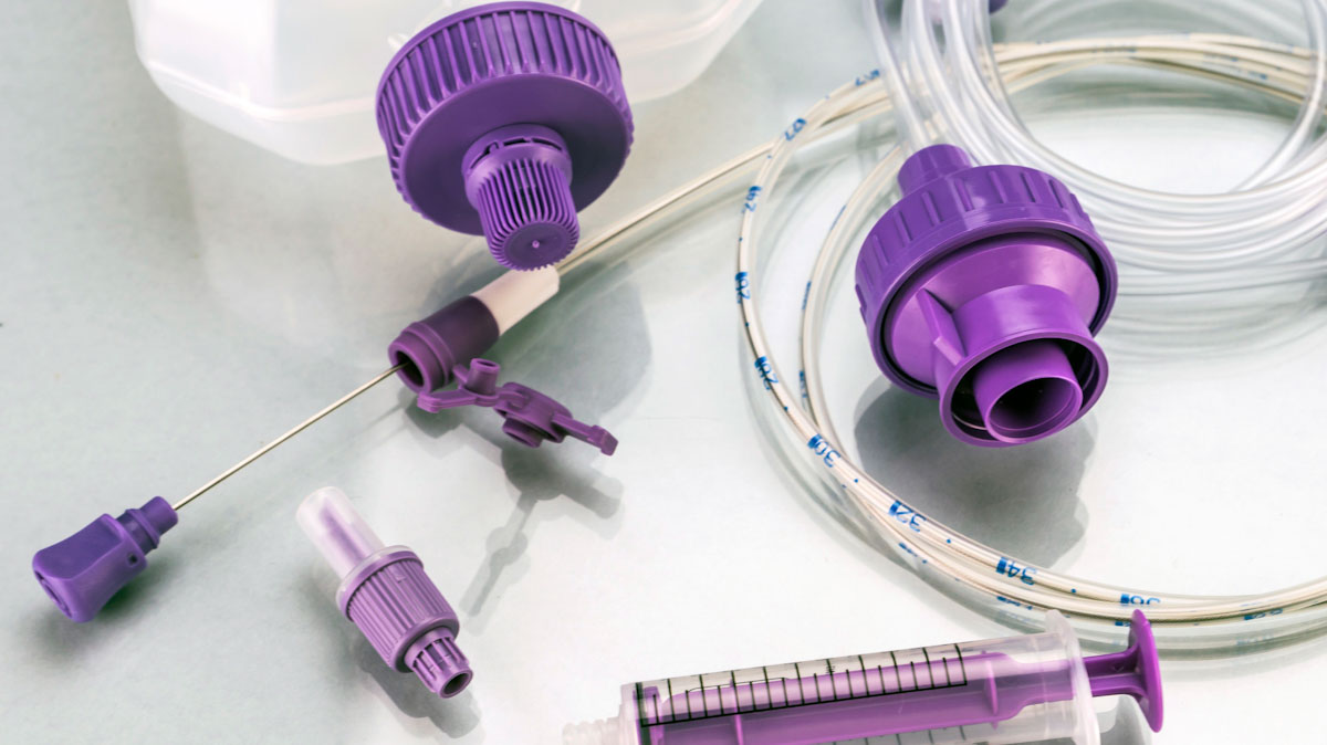 An assortment of equipment for home enteral nutrition, including tubes, a syringe and a bottle.