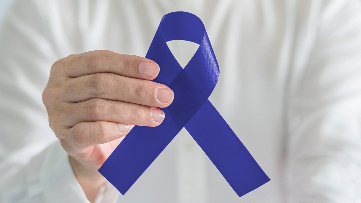 Man holding a blue ribbon, which represents colorectal cancer.