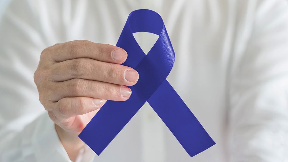 Man holding a blue ribbon, which represents colorectal cancer.