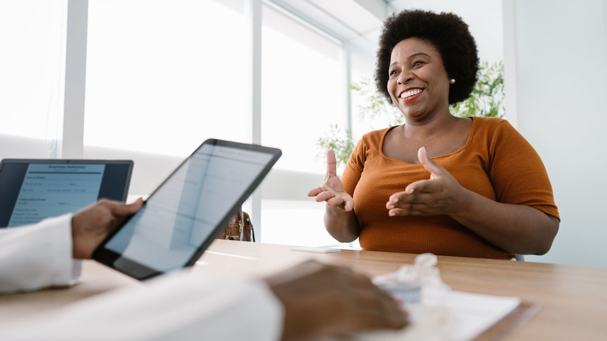 A smiling individual sits in front of a dietitian during an appointment.