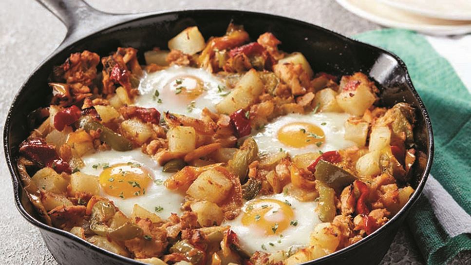 A cast iron pan full of tuna hash with four sunny-side up eggs on top.