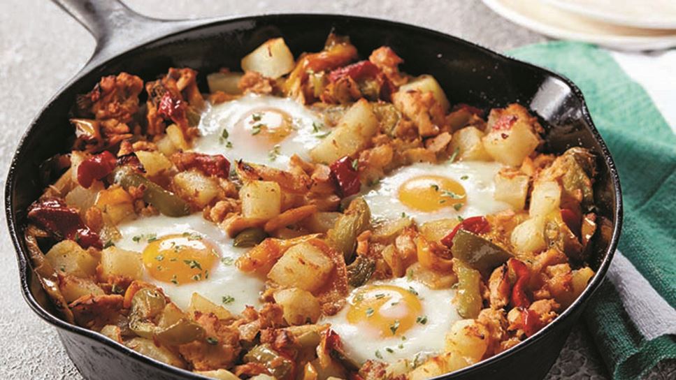 A cast iron pan full of tuna hash with four sunny-side up eggs on top. 