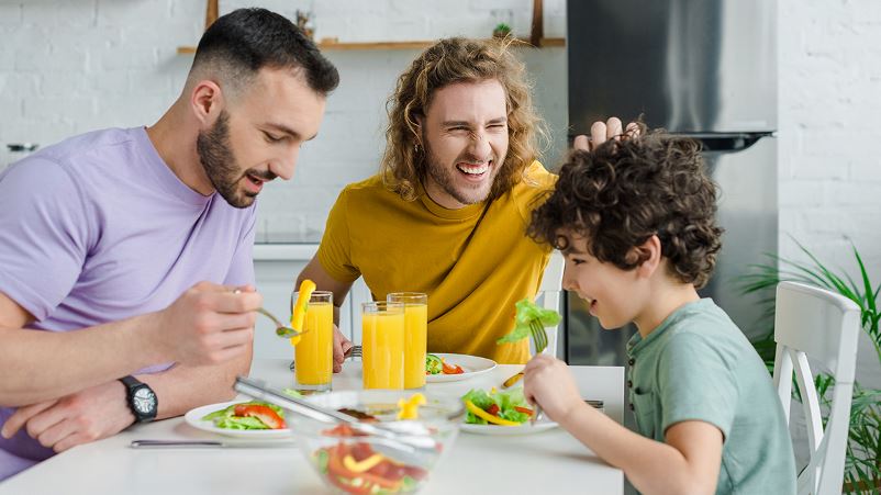 Two men are eating salads with their son or younger brother, showing the importance of vegetables for men's health.