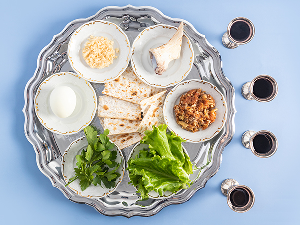 A pesach plate with traditional symbols of the Jewish Passover and four glasses of red kosher wine