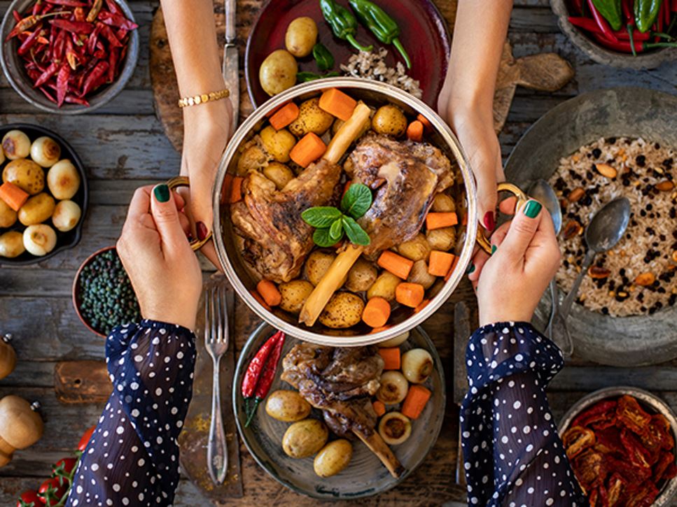 Two people eating lamb, potatoes, carrots and more traditional foods for Eid al-Adha celebration