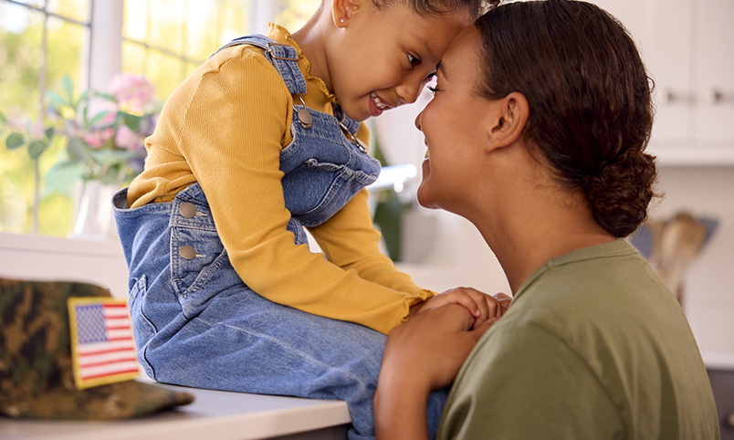 military solder and parent sitting in kitchen with child
