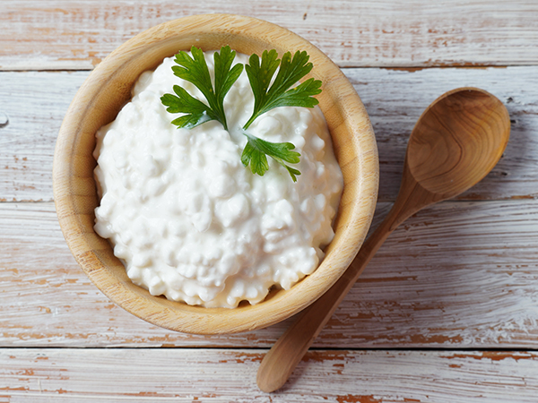 Plain small curd cottage cheese in a bowl with a wooden spoon