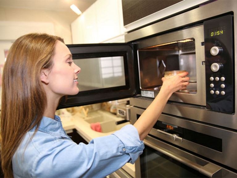 woman putting food in microwave