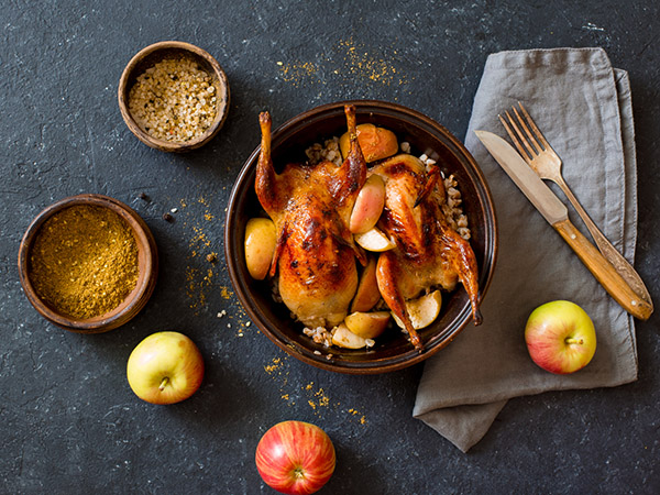 Two cooked quail in pot with apples