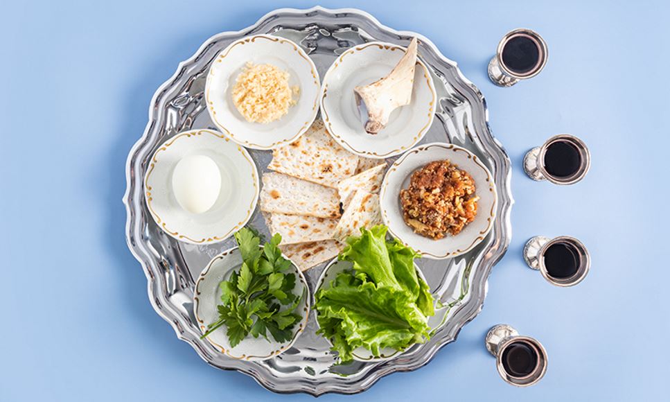 A pesach plate with traditional symbols of the Jewish Passover and four glasses of red kosher wine