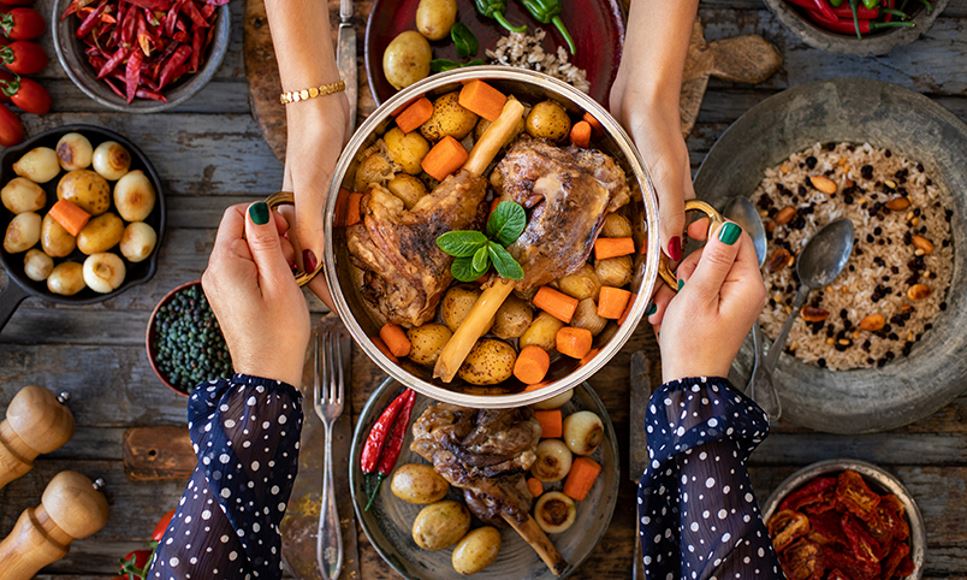 Two people eating lamb, potatoes, carrots and more traditional foods for Eid al-Adha celebration