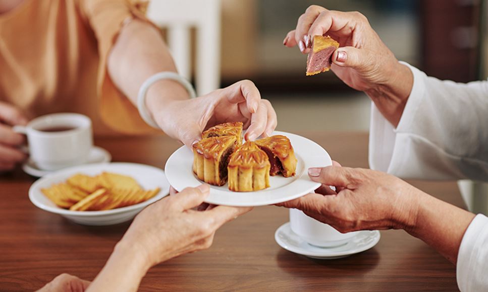 Family and friends enjoy slices of mooncake, a traditional food eaten during the Mid-Autumn Festival celebration.