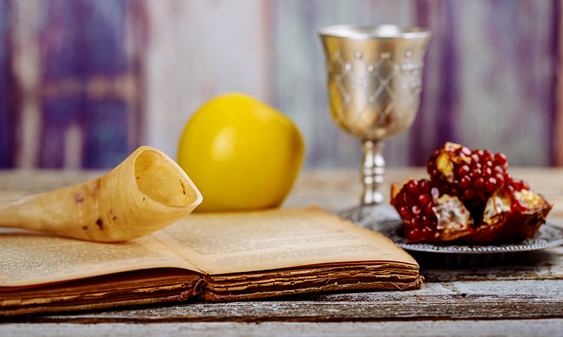 Apple and pomegranate on wooden table over bokeh background to show Yom Kippur traditions