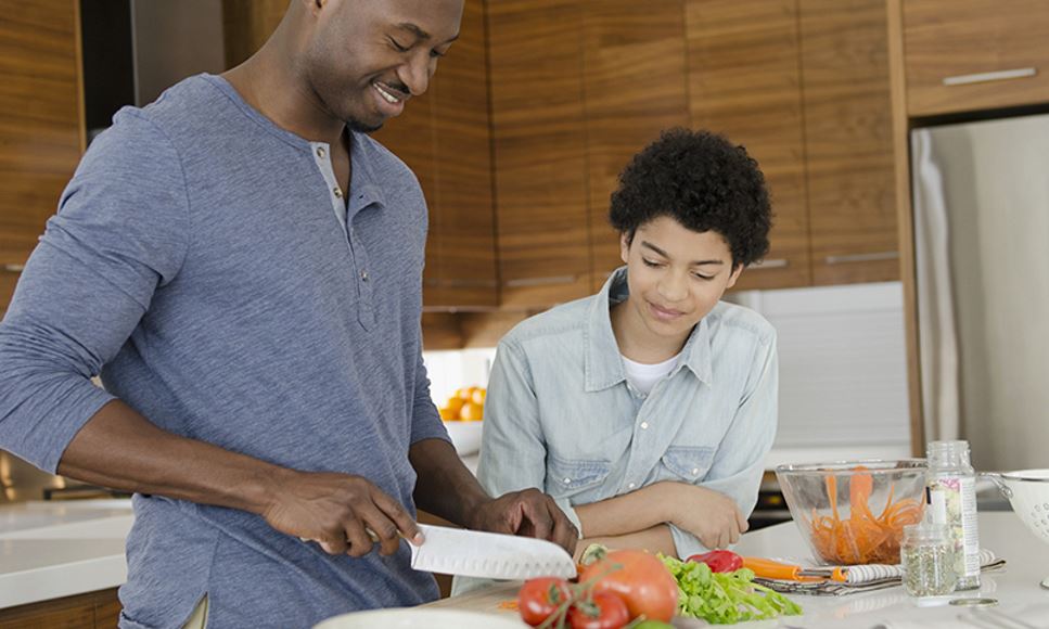Father and son prepare a healthy salad together as a family during August for Kids Eat Right Month.