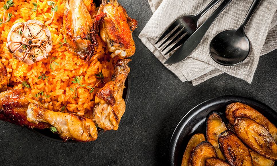 plate of african food including jollof rice, chicken and plantains
