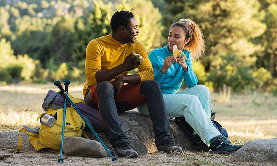 couple taking a break from hiking to have a snack of fresh fruit