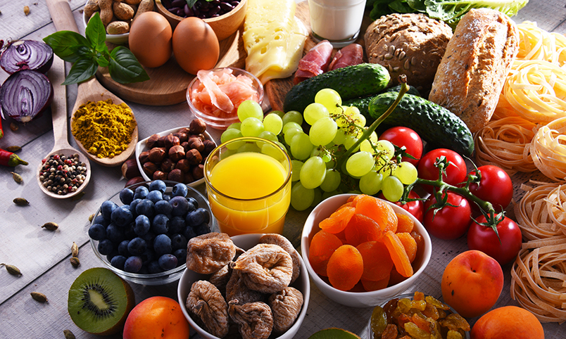 An assortment of food from all food groups including fruits, vegetables, whole grains, protein foods, dairy and fats.