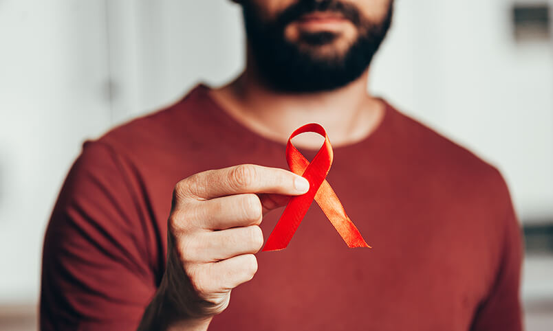 man holding red ribbon representing HIV/AIDS