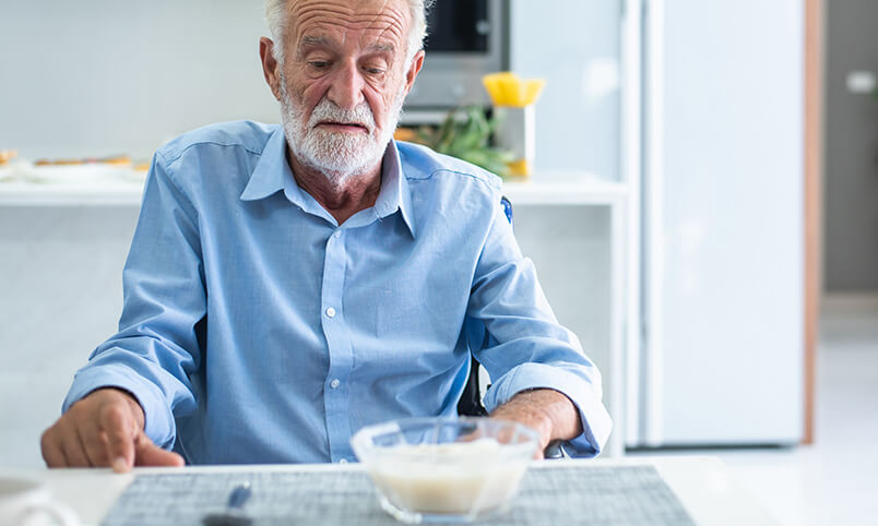 older adult man looking at bowl of food