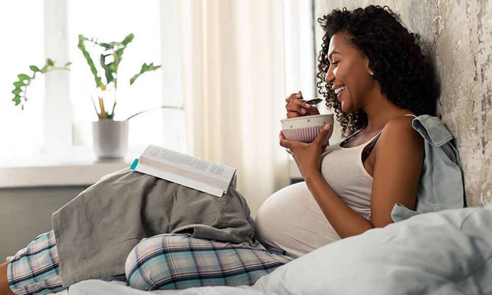pregnant woman lying in bed eating