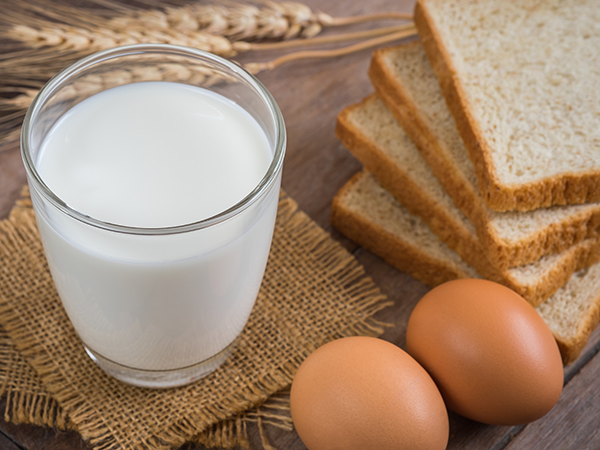 Milk, eggs and whole-wheat bread are sitting on a counter in preparation for making cinnamon french toast for breakfast.